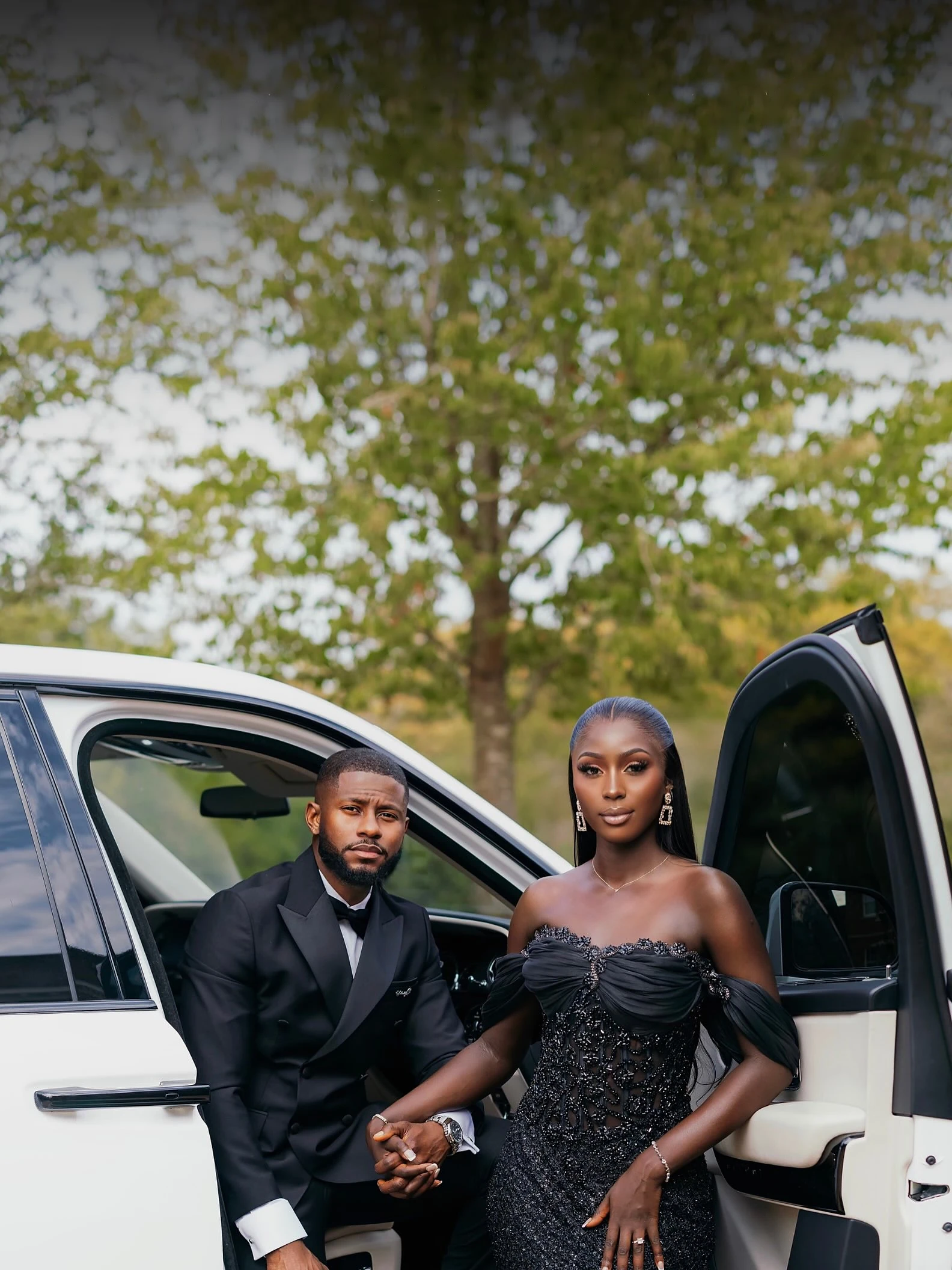 Mr and Mrs Sanyang in black formal wear beside a white car, from the artwork for their 8ft welcome board